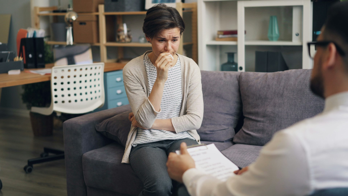 a woman sitting on a couch talking to a man